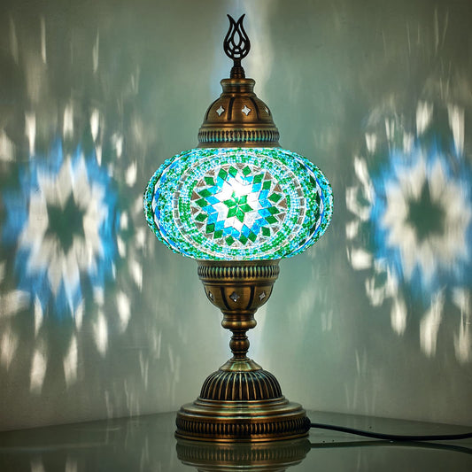 Turkish Moroccan mosaic bedside lamp featuring a globe‑shaped glass shade with colorful mosaic tiles and an ornate bronze base, casting warm, patterned light